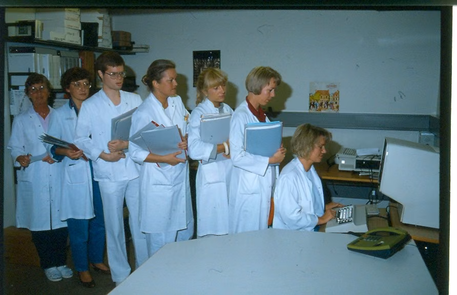 Sygehuspersonale samlet om en terminal, ca. 1980